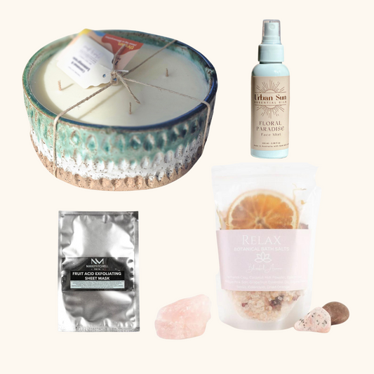 Collection of self-care products including a candle, facial mask, and spray bottle on a white background