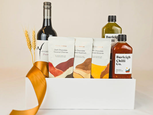 Gift hamper with red wine, chocolates and two chilli sauce bottles.