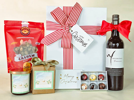Gift basket with cashews, wine, and other items on a light background