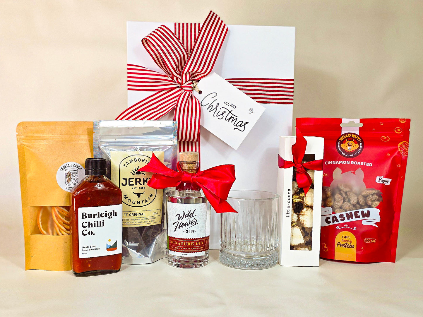 Gift basket with various items including a bottle, snacks, and a glass on a beige background