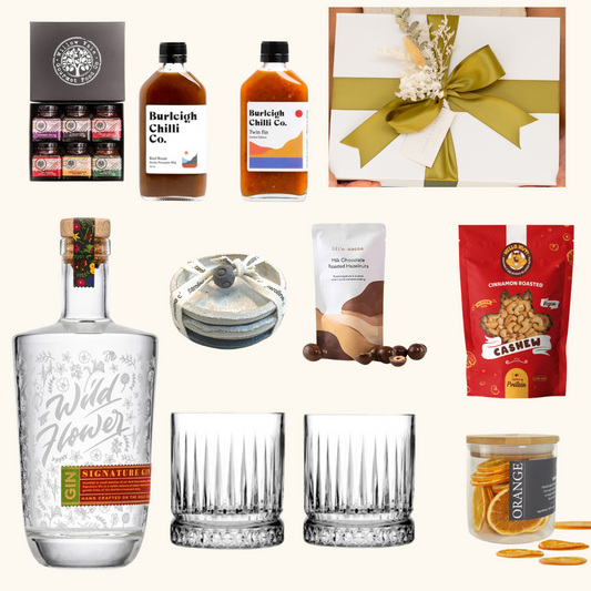 Collection of items including a bottle of Wild Flower gin, glasses, and various snacks on a white background.