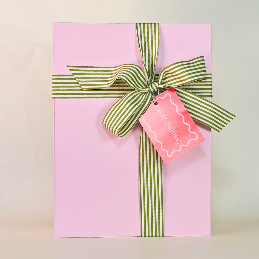 Pink gift box with a green striped ribbon and a pink tag on a light background