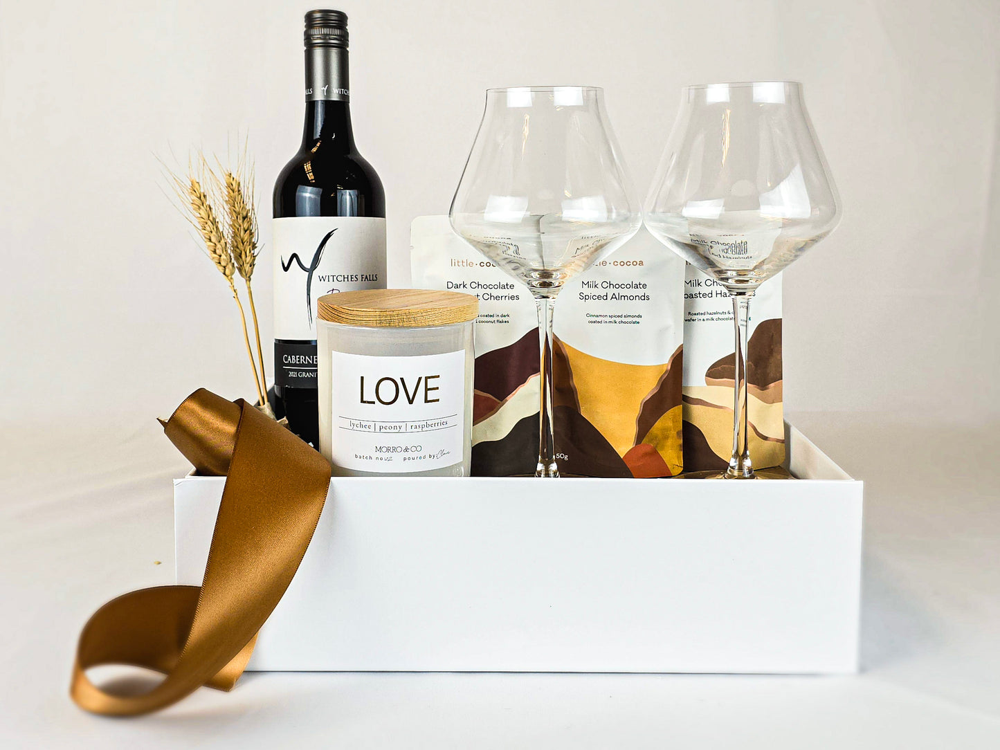 Gift hamper with red wine, candle wine glasses and chocolates.