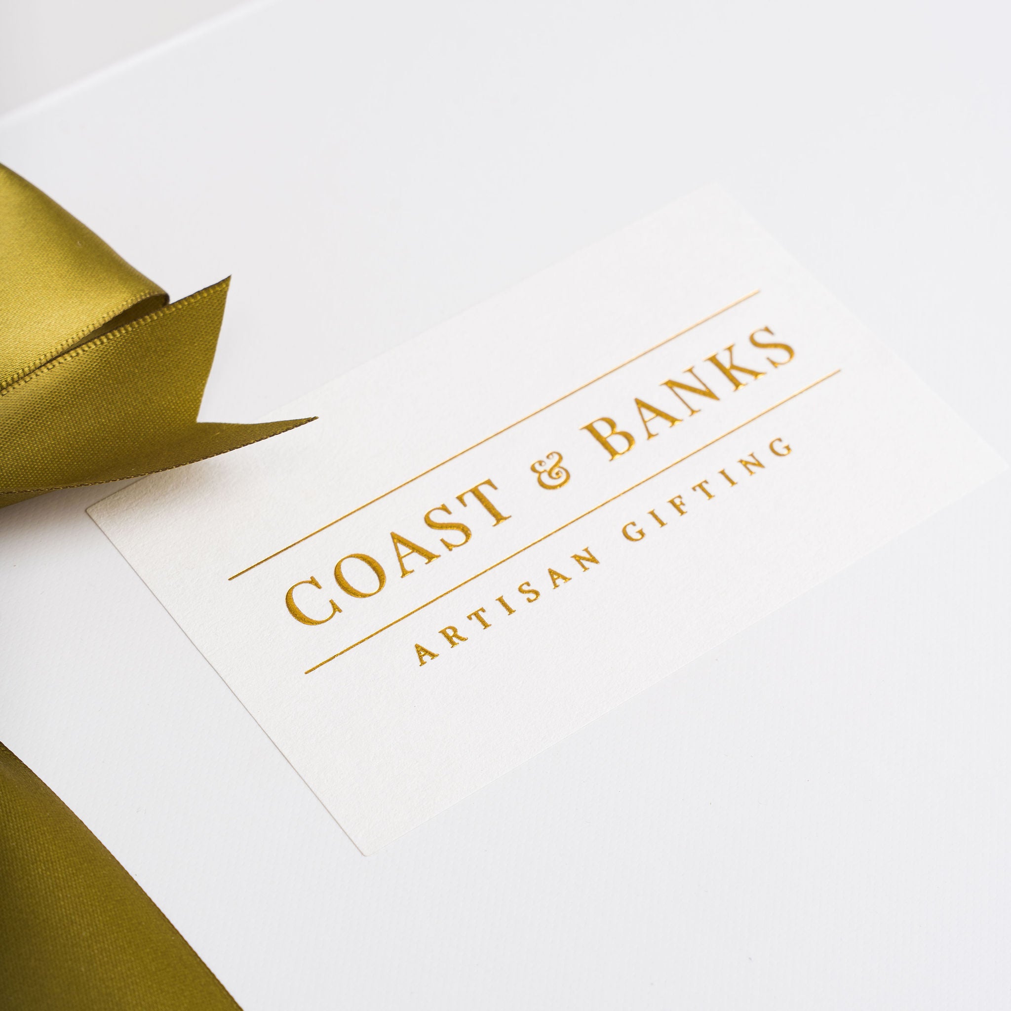 White box with gold ribbon and 'Coast & Banks Artisan Gifting' text on a white background