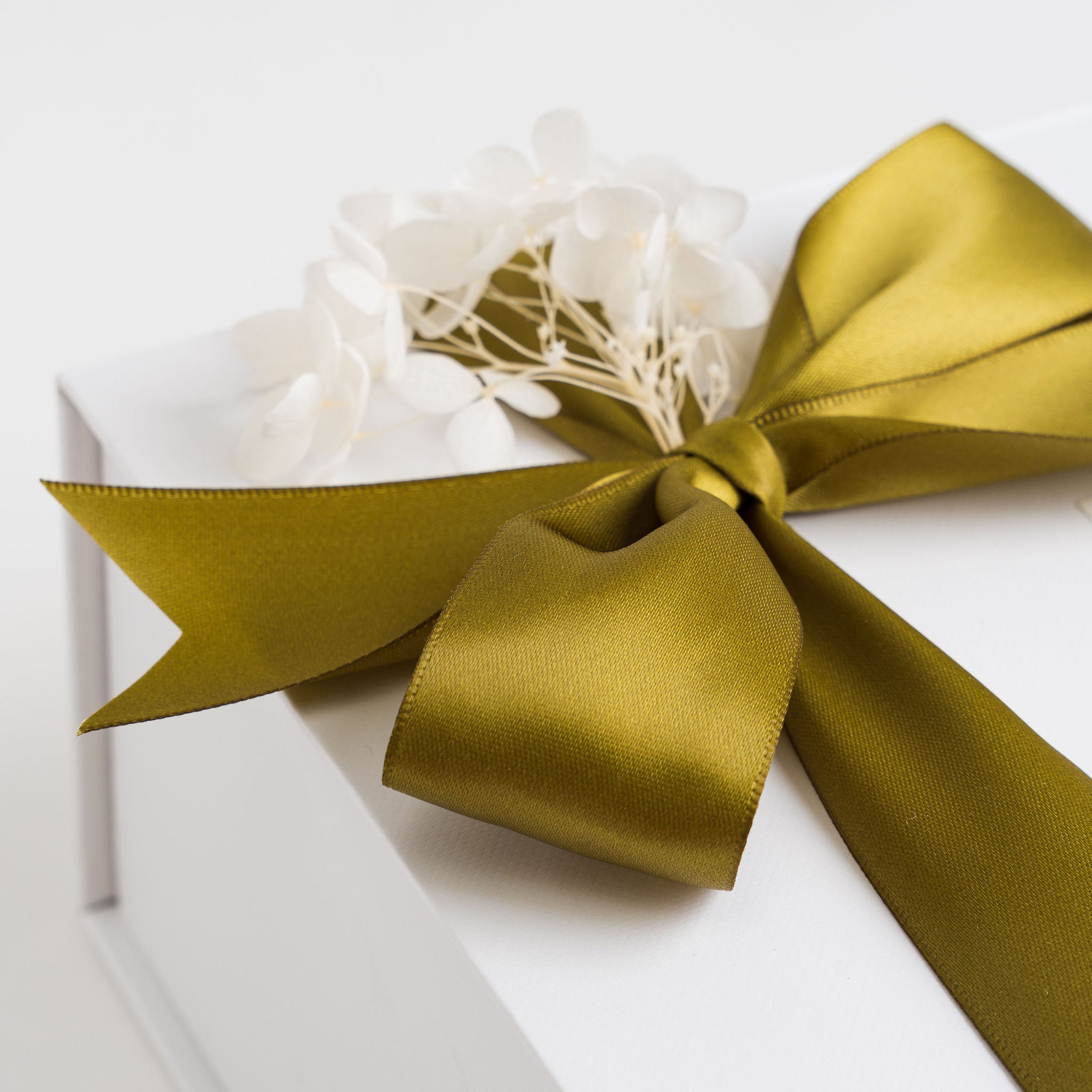 Gift box with a green ribbon and white flowers on a white background