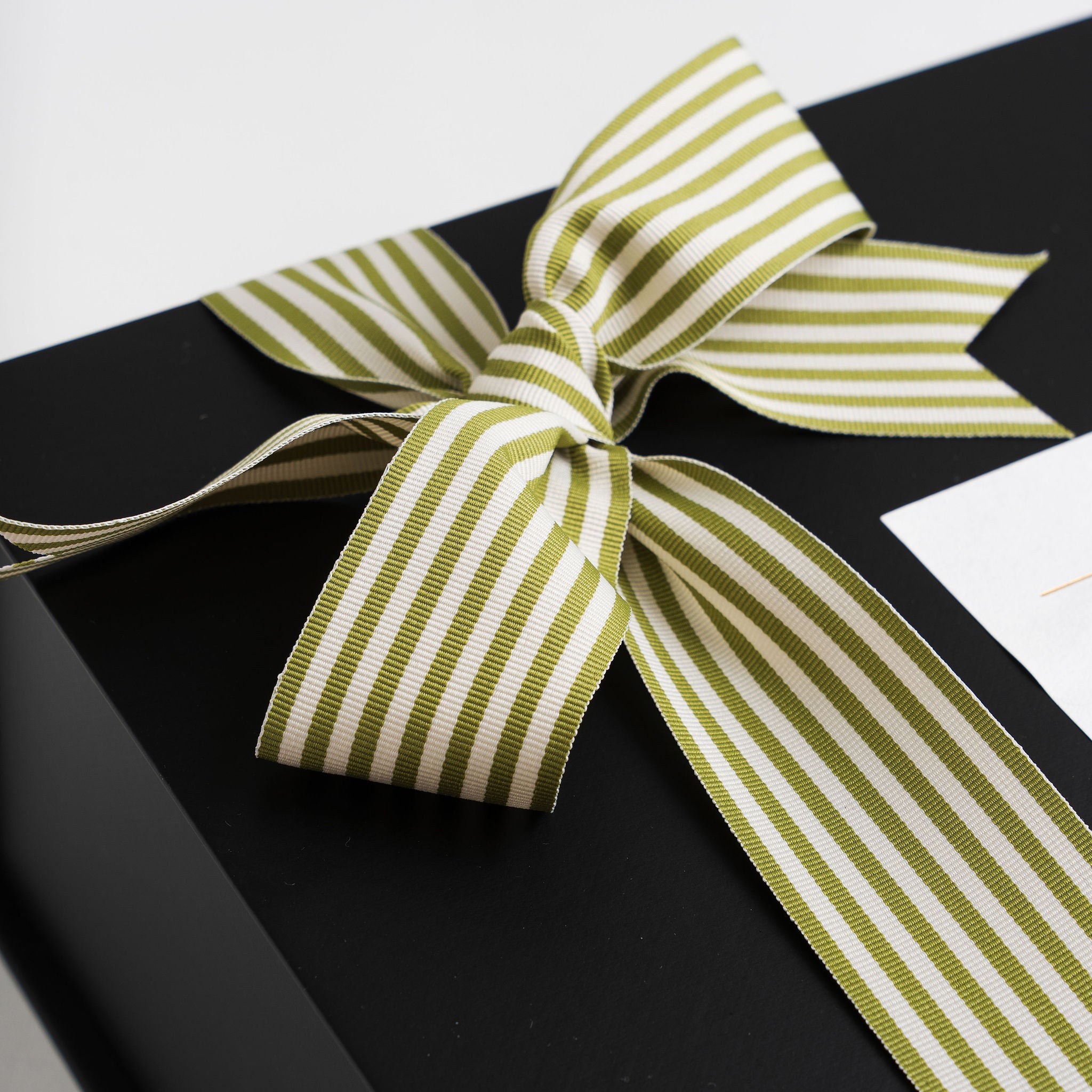 Black gift box with a green and white striped ribbon on a white background
