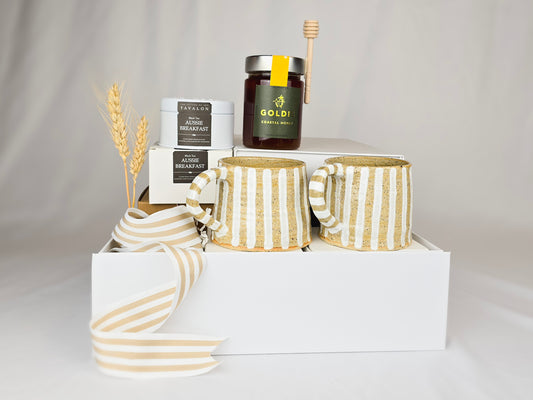 Gift hamper with two handmade ceramic mugs, tea and honey.