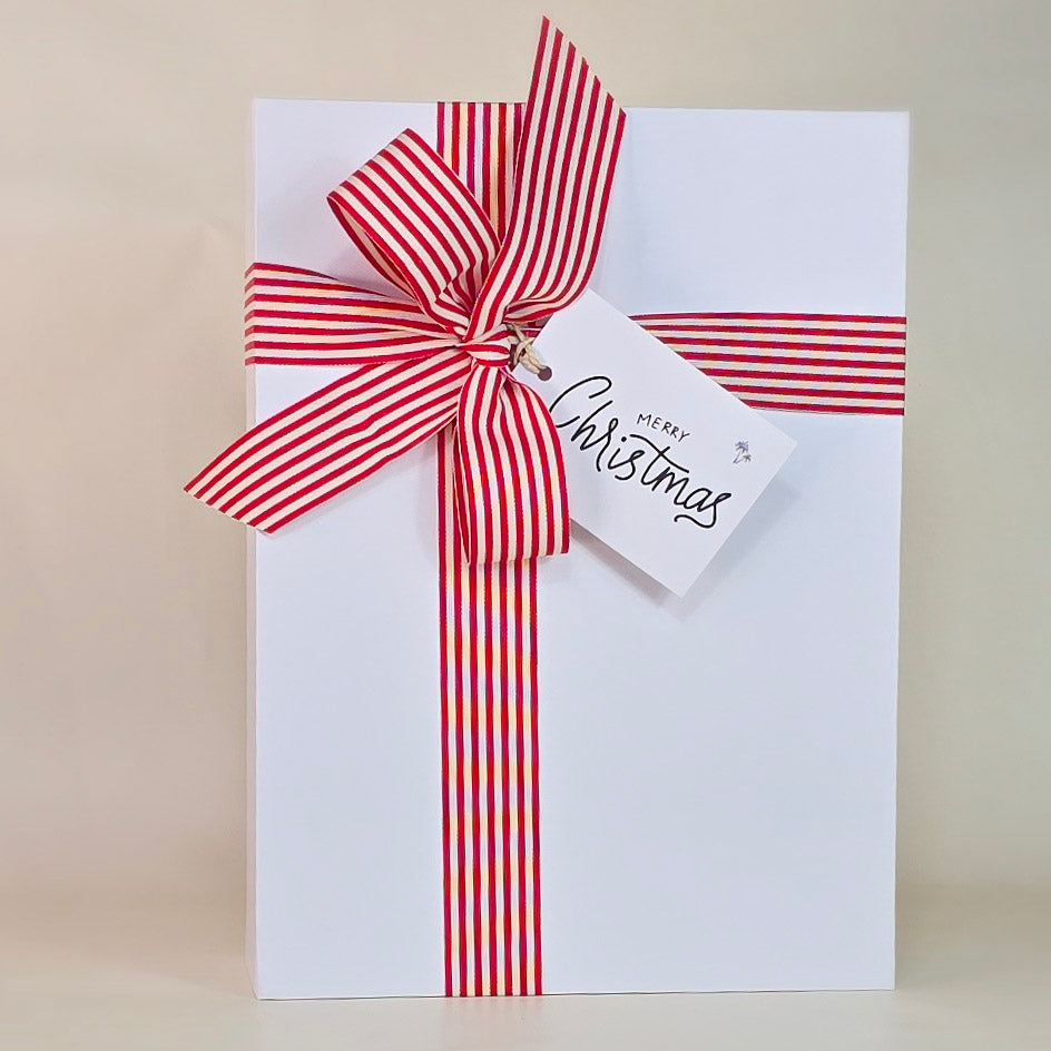 White card with a red and white striped bow and 'Merry Christmas' tag on a beige background