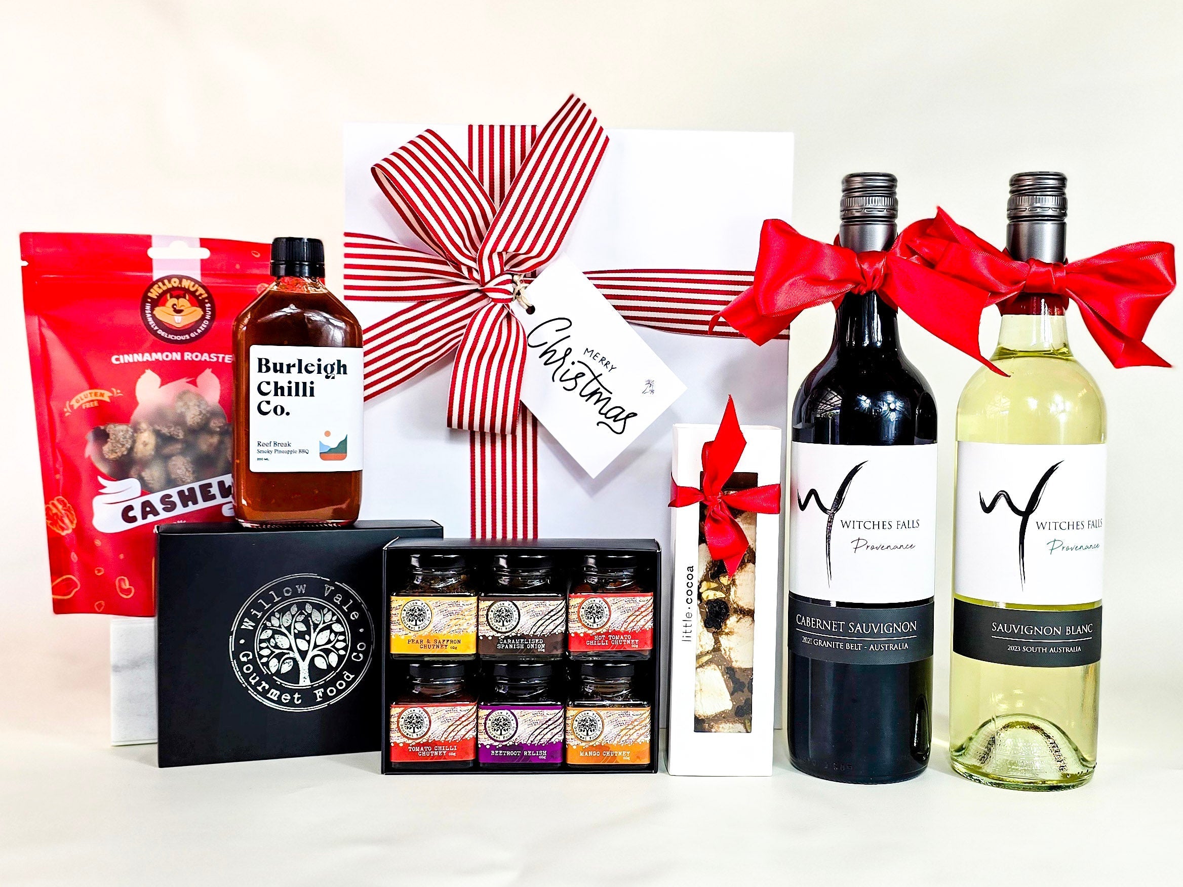 Christmas Hamper with wone, relish, chocolate, chilli sauce and cinnamon cashews. Strip ribbon with white bix.