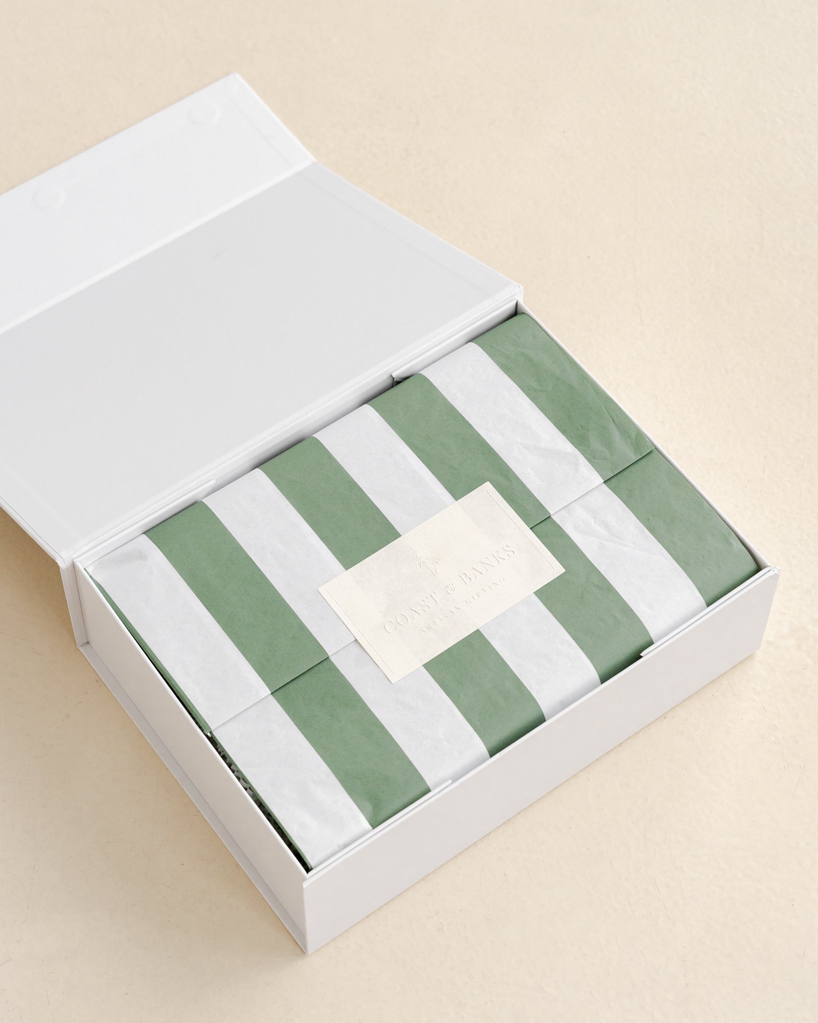 Green and white striped tissue paper in a white box on a beige background