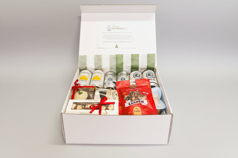 Gift box with beer bottles, snacks, and a card on a wooden surface
