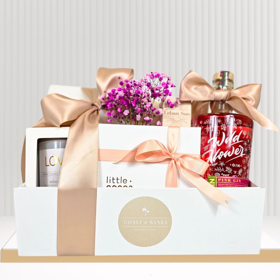 Gift hamper with pink gin, chocolates, candle and face mist.
