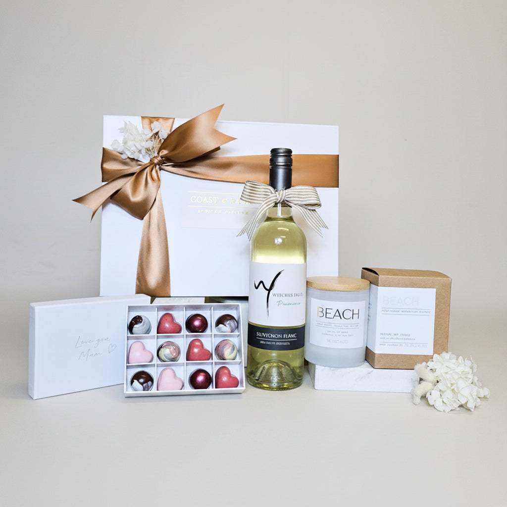 Wine bottle, chocolates, and candles on a wooden surface with a neutral background
